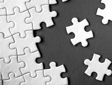 Close-up view of white jigsaw puzzle pieces on grey background